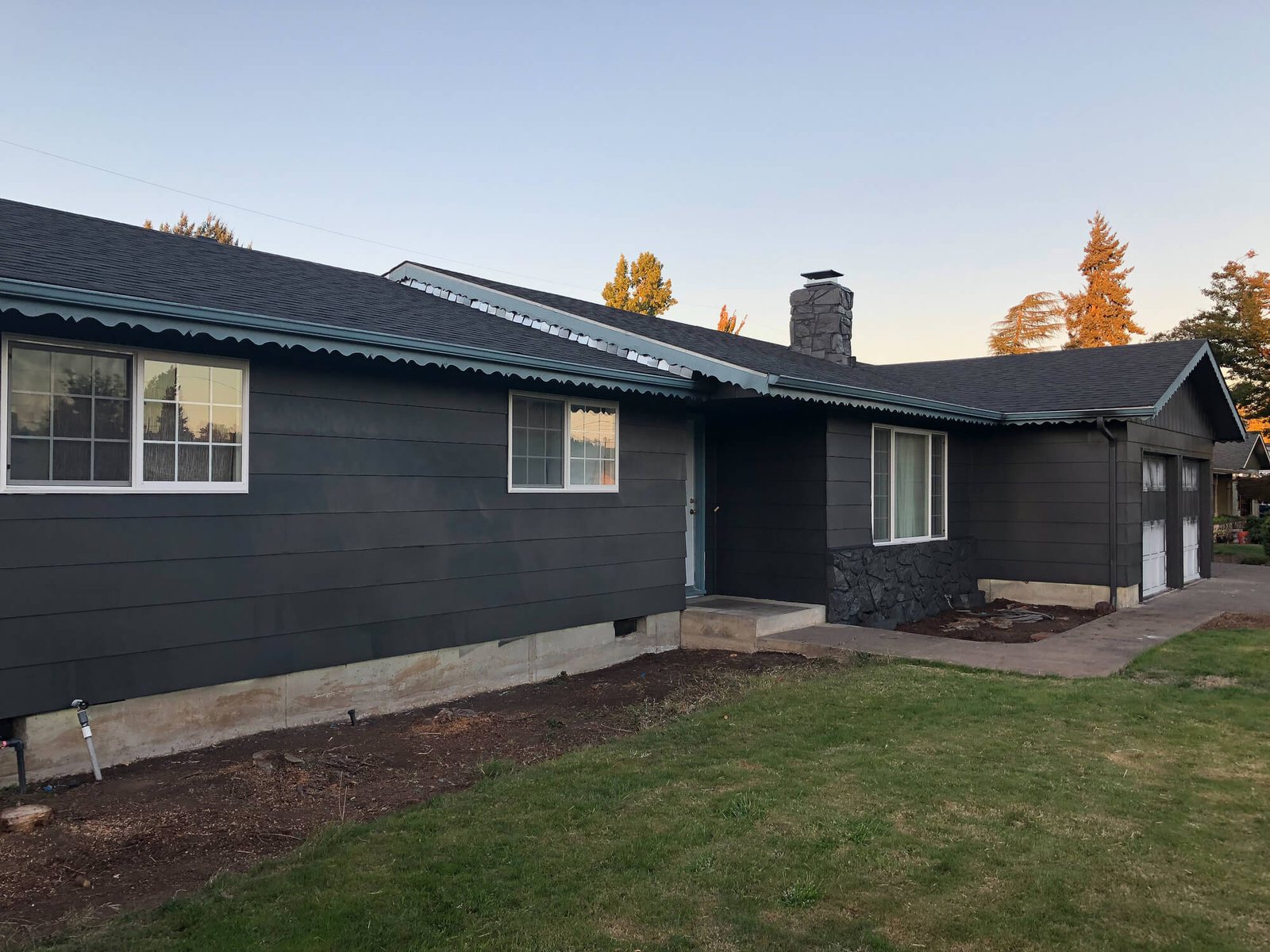 Single story house in a dark finish seen from the lawn