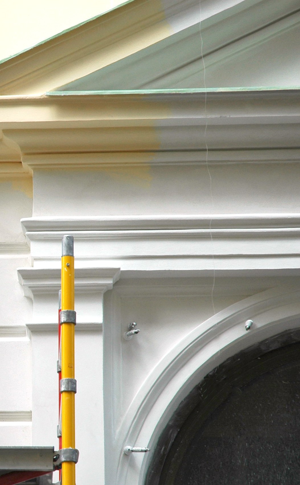 Cornice and arched doorway with a fresh white coat carried over an older cream finish
