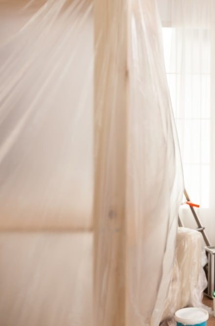 Interior room with the furniture and doorway taped under plastic sheeting
