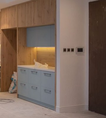 Blue kitchen cabinets and oak units under warm task lighting