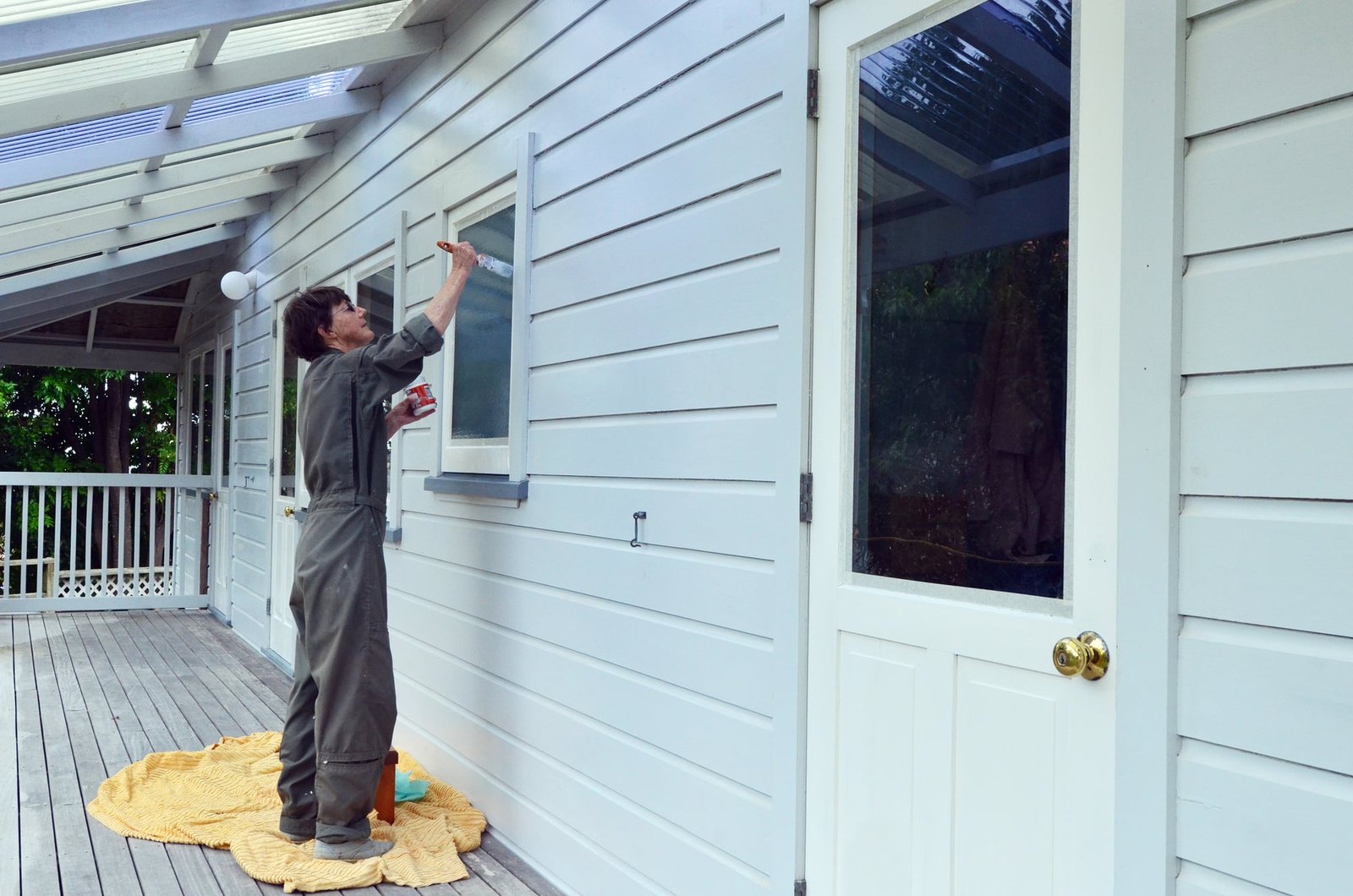 Cutting in window trim by hand on a shaded clapboard porch