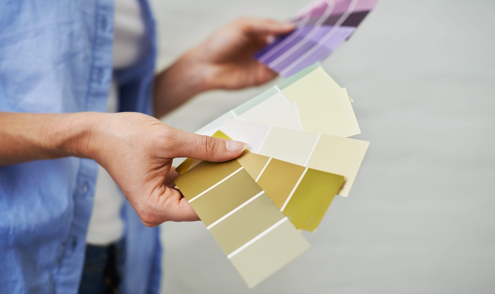Holding a fan of paint chips up against a wall to compare colors