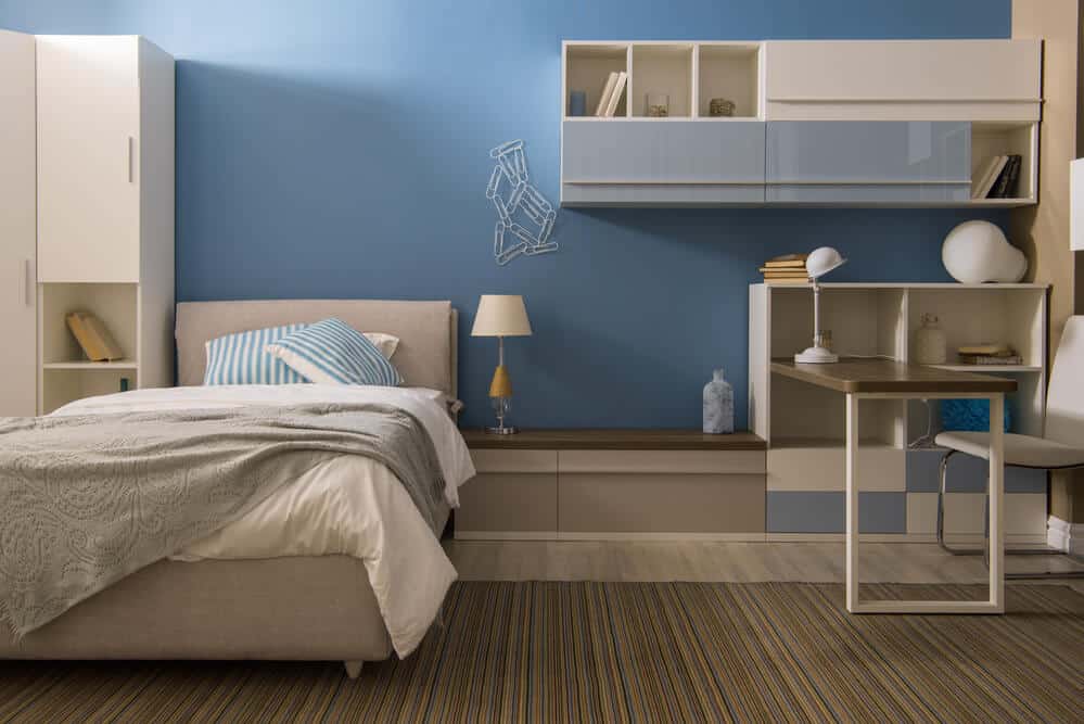 Bedroom finished in a blue gray with a built in desk