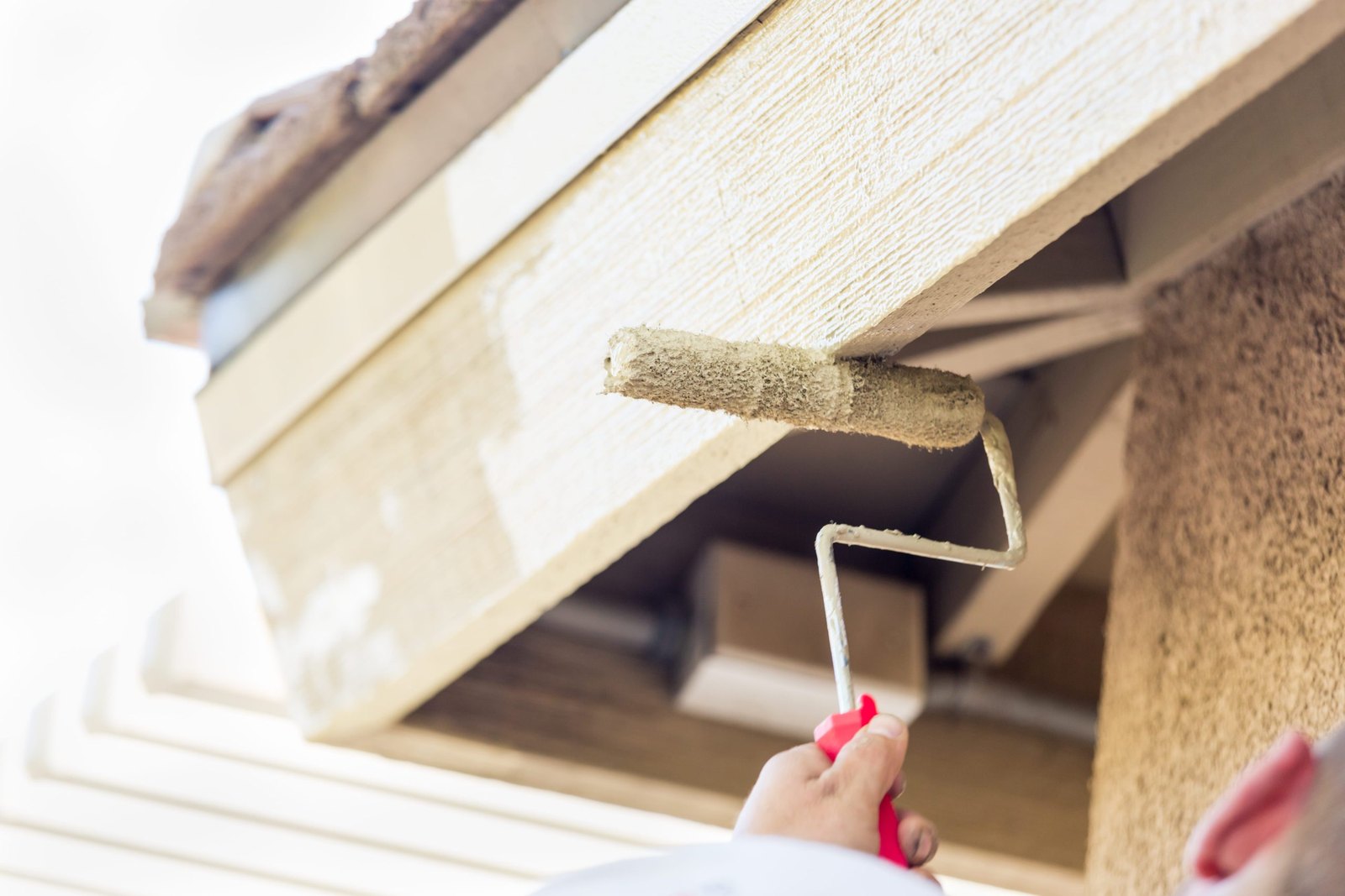 Rolling paint onto a fascia board under the roof edge