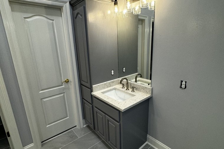 Gray linen tower and vanity beside a white panel door, against blue gray walls