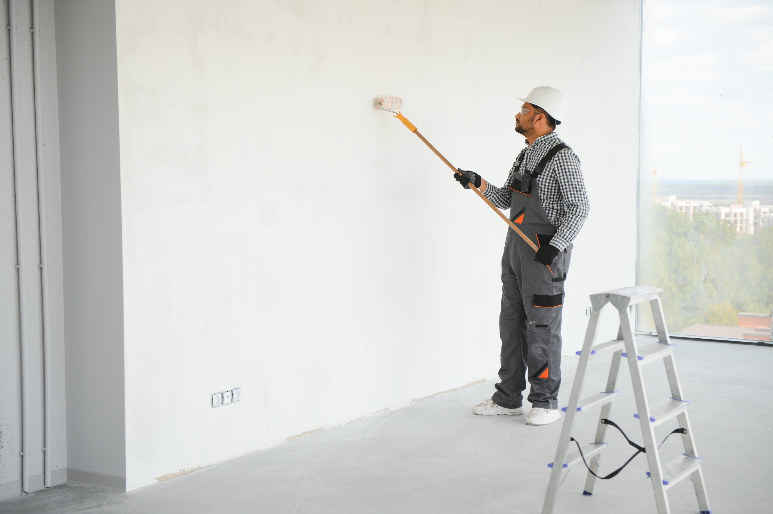 man painting stucco wall